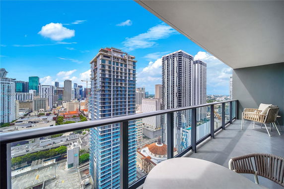 Panoramic view from a high-rise building balcony overlooking a cityscape with multiple skyscrapers.