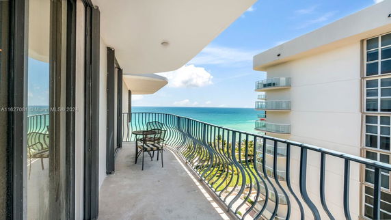 Balcony with view of ocean and nearby buildings.