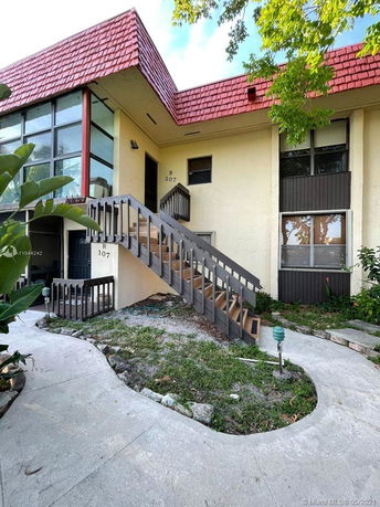 Front view of a two-story residential building with exterior stairway and red roof.