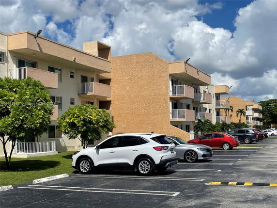 Outdoor view of a multi-story building with a parking area in front.