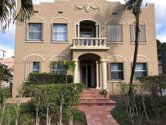 Front view of a two-story house with arched windows and a decorative balcony.
