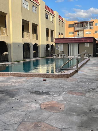 Outdoor swimming pool area adjacent to a multi-story building.