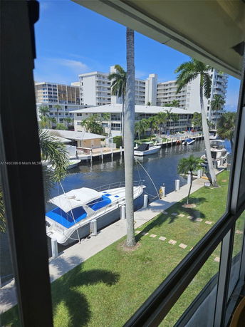 View from a window showing a canal with boats and nearby residential buildings.