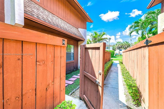 Front view of a two-story house with a wooden fence and gate.