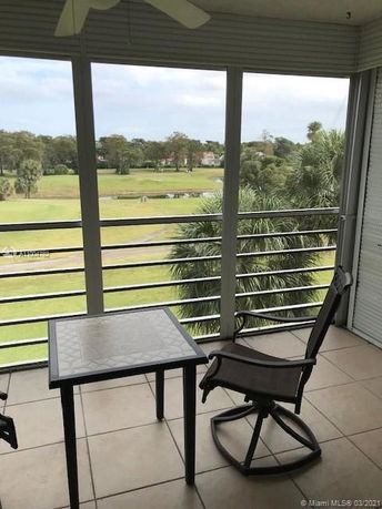 Panoramic view from a balcony overlooking a grassy area and trees.