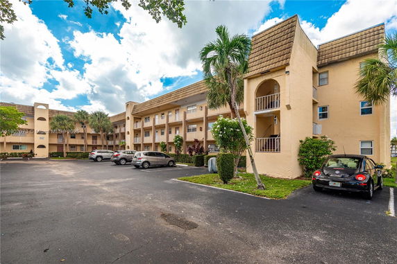 Front view of a multi-story apartment building with balconies and parking area.