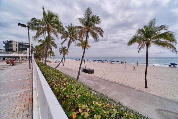 Beachfront area with palm trees and a nearby building.
