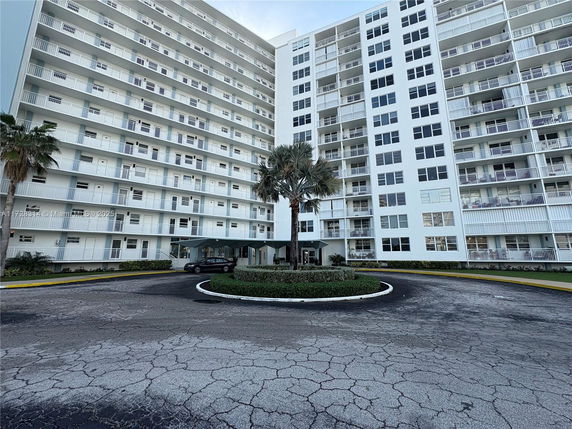 Front view of a multi-story building with balconies and a roundabout entrance.