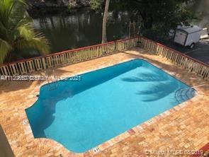 Swimming pool with surrounding brick patio area and view of nearby water body.