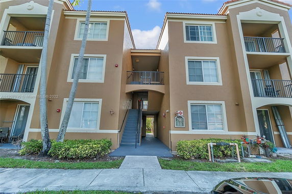 Front view of a multi-story apartment building with balconies and a central staircase.