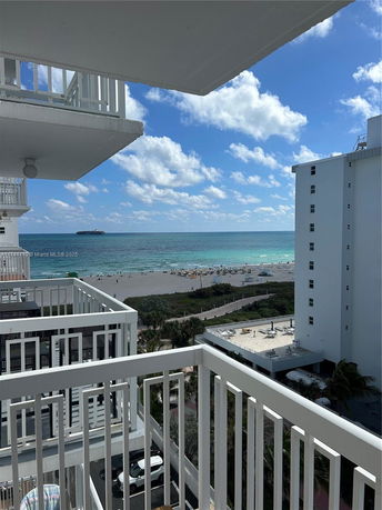 View from a balcony overlooking the ocean with beach and buildings.