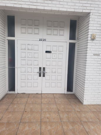 Front view of a white brick building entrance with double doors.