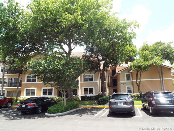 Front view of a multi-story residential building with a parking area.