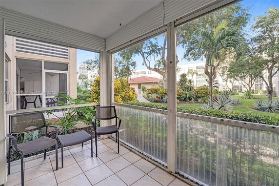 View from a screened porch overlooking landscaped gardens and nearby buildings.