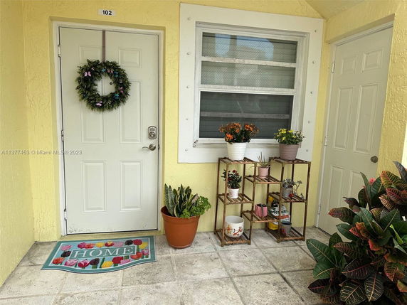 Front view of a house entrance with plants and decorations.