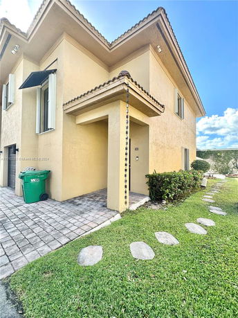 Front view of a two-story house with a tiled roof and stone walkway.