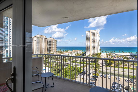 Panoramic view of ocean and surrounding buildings from a balcony.