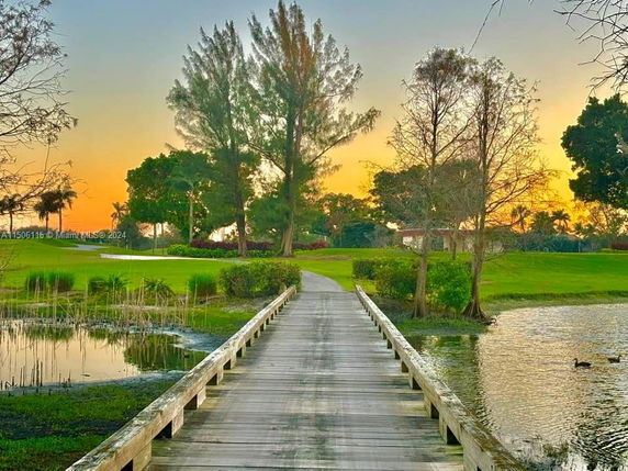 Pathway leading through a park landscape with trees at sunset.