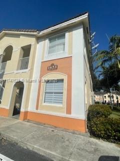 Front view of a two-story building with arches and a light color scheme.