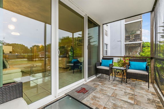 View from a balcony with outdoor seating, overlooking nearby buildings and greenery.