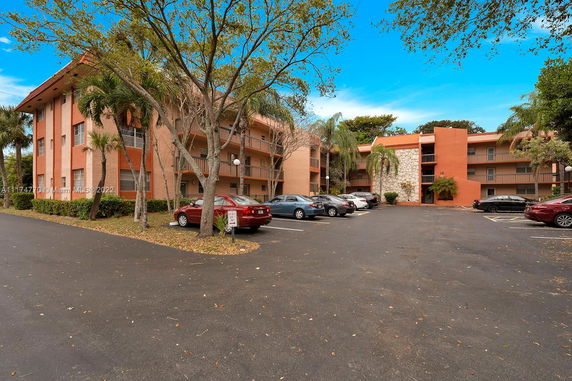 Front view of a multi-story apartment building with a parking area in front.