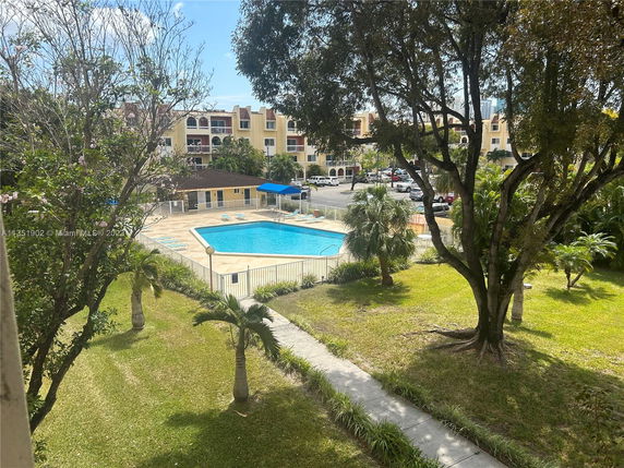Outdoor swimming pool area with surrounding trees and a building in the background.