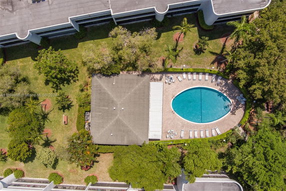 Aerial view of a swimming pool next to a building surrounded by trees.