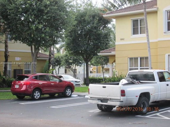 Outdoor parking area with parked vehicles in front of a building.