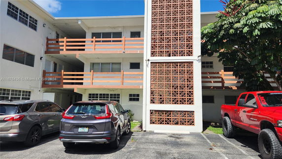 Outdoor view of a multi-story building with several parked cars in front.