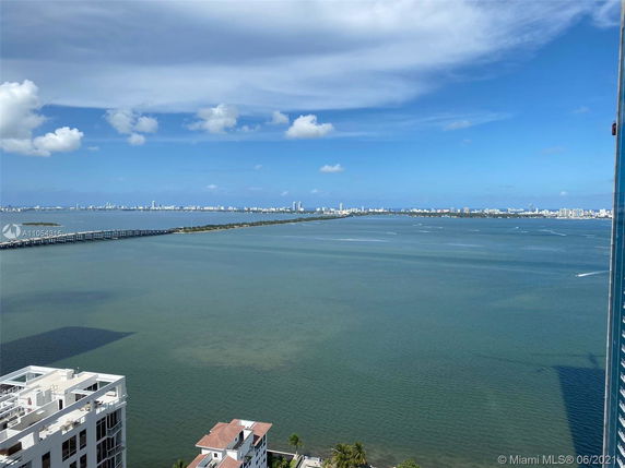 Wide angle view of a coastal cityscape with water and buildings in the distance.