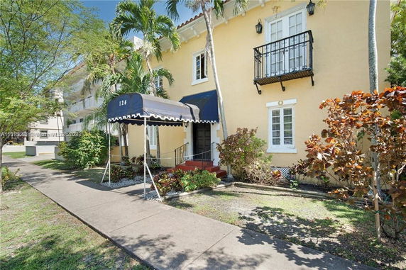 Front view of a two-story building with a small balcony and a blue canopy over the entrance.