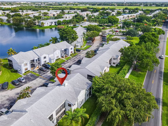 Aerial view of residential neighborhood with parking and nearby water body.