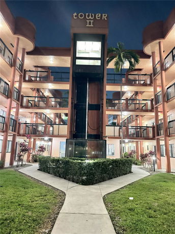 Front view of a multi-story building labeled Tower II with balconies and an external elevator.