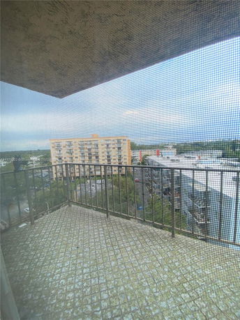 View from a balcony with a railing, overlooking nearby buildings and landscape.
