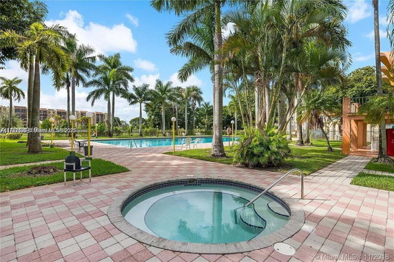 Outdoor area with swimming pool surrounded by palm trees.