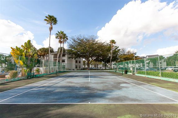 Tennis court with green fence and trees surrounding it.