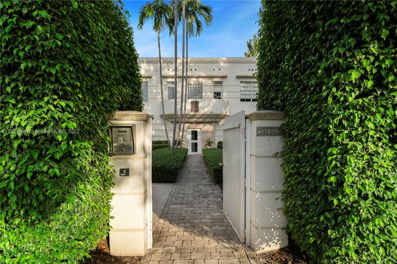 Front view of a two-story building with gated entrance and lush greenery.