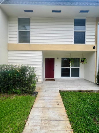 Front view of a two-story house with a red door and light-colored siding.