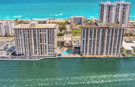 Aerial view of tall beachfront apartment buildings with ocean in the background.