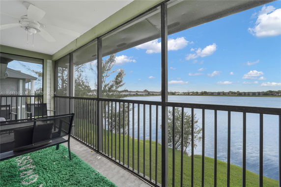 View from a screened balcony overlooking a lake with surrounding landscape.