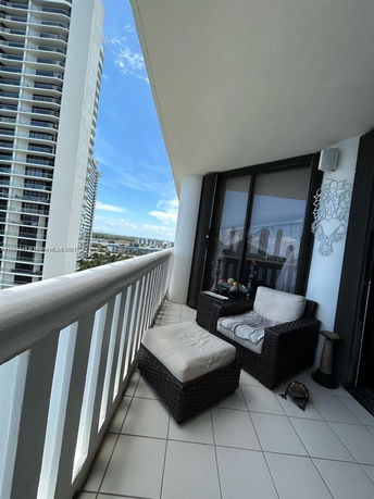 Balcony view over a cityscape with tall buildings and a clear sky.
