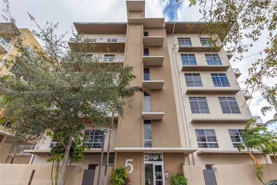 Front view of a multi-story apartment building with large windows and balconies.