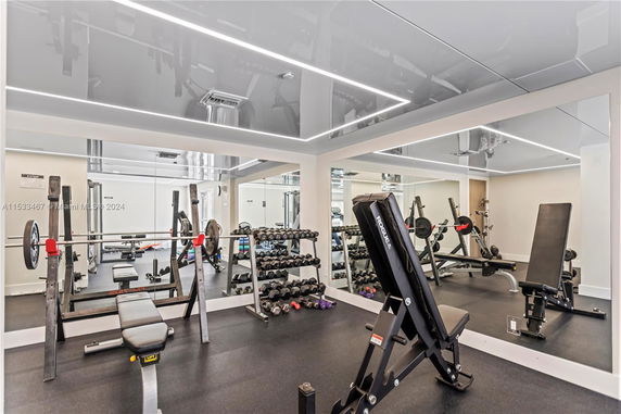 Indoor gym with weight benches, dumbbells, and mirrored walls.