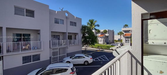 View of a parking area and residential buildings with balconies.
