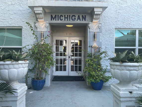 Front view of a building entrance with decorative columns and planters.