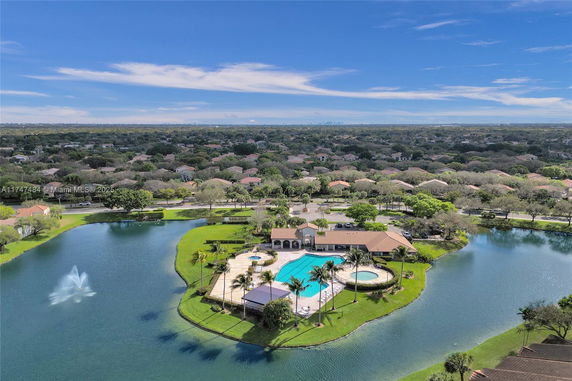 Wide view of a residential neighborhood with a central recreational area including a swimming pool and a lake.