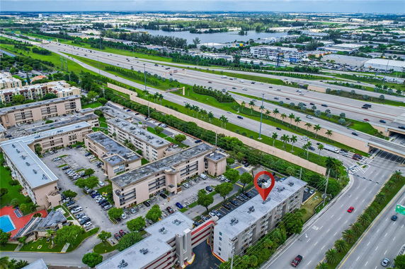 Aerial view of a residential area near a highway with multiple buildings and parking spaces.