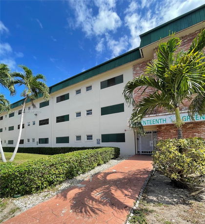 Front view of a multi-story building with green shutters and a brick facade.