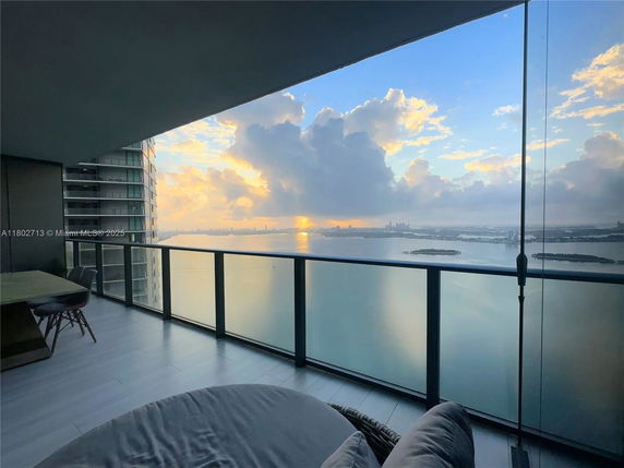 Panoramic view from a high-rise balcony overlooking water and city skyline.