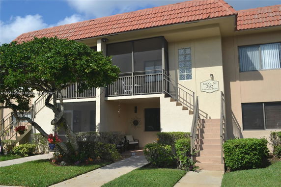 Front view of a two-story residential building with a tile roof and exterior stairs leading to the upper level.